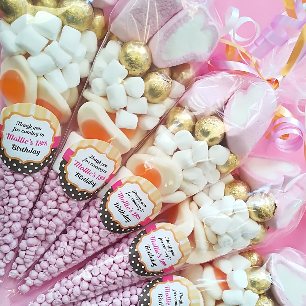 Decorative candy bags with gold, white, and pink colours, featuring personalised labels.