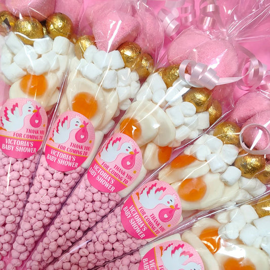 Cones filled with pink and gold candy and marshmallows, labeled for a baby shower.