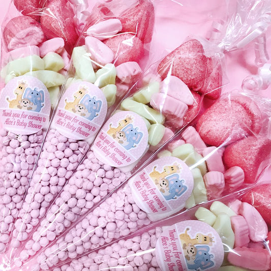 Pink sweet candy bags with baby shower labels on a pink background