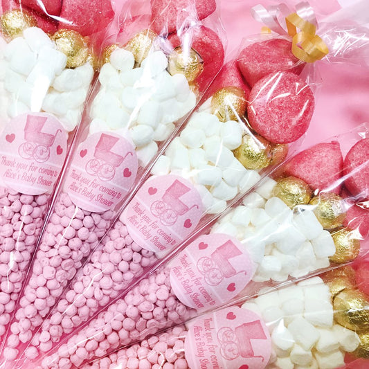 Assorted sweets in clear bags with pink labels for a baby shower.