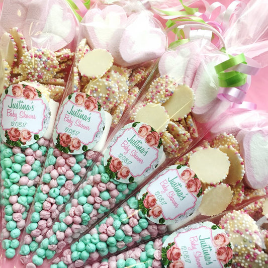 Decorative baby shower favour bags with pink and green candies and floral labels.