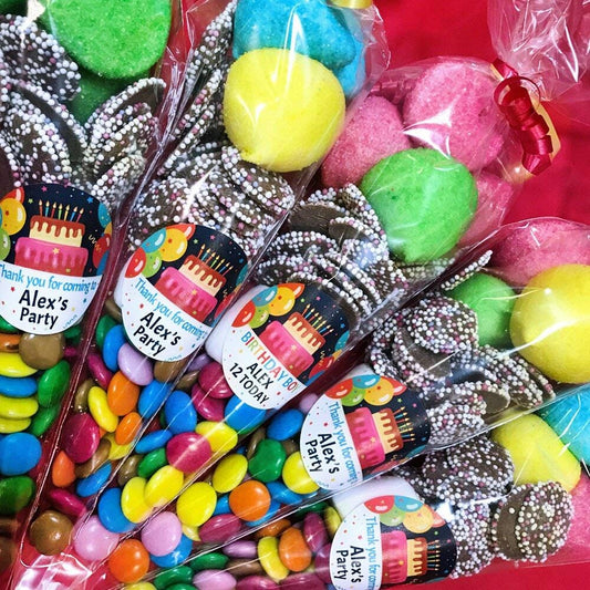 Pre-filled sweet cones with a birthday theme, containing various candies and chocolates, packaged and labeled for party favors.