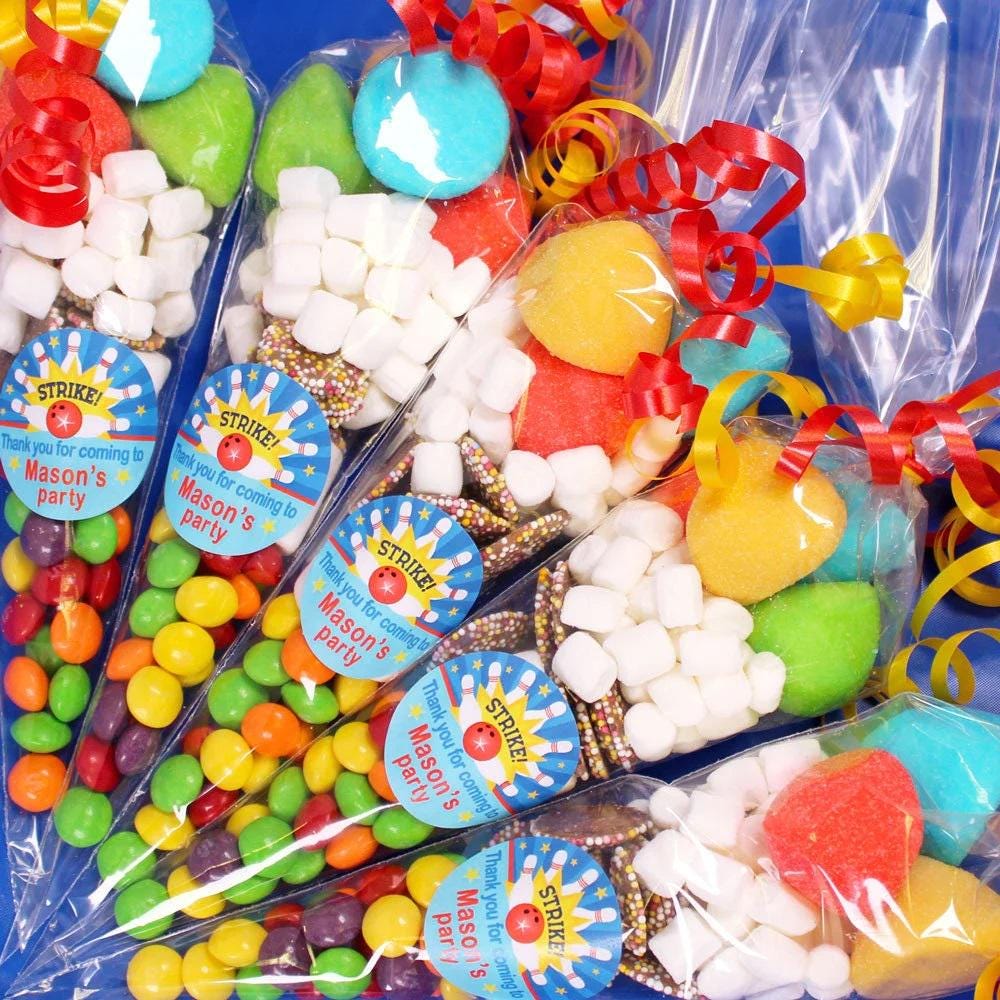 A selection of pre-filled sweet cones designed for bowling party favours, with various colorful candies visible inside the cones, sealed in transparent packaging.