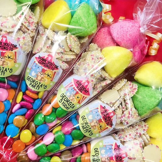Assorted candies and cookies in clear packages with personalized labels for a birthday party.