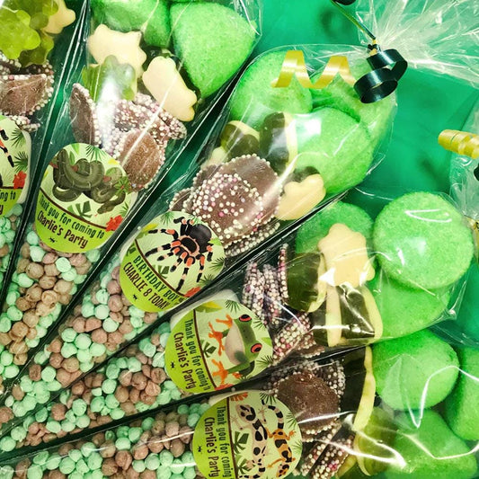 Packaged sweet cones with various candies visible through the clear plastic, decorated with green wrapping and party-themed stickers.