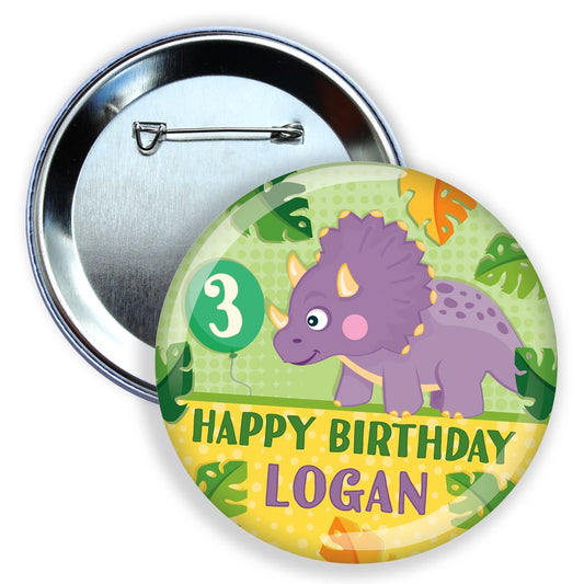 Button badge with a dinosaur design, number 3, and 'Happy Birthday Logan' text on a green and yellow background.