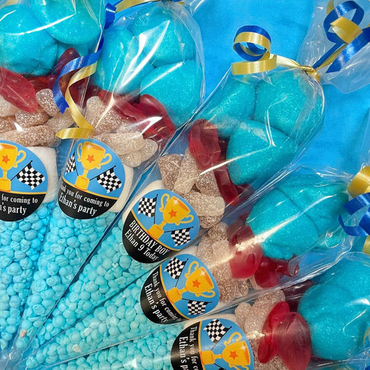 Party favors with blue and red gumballs and decorative ribbons in clear bags.
