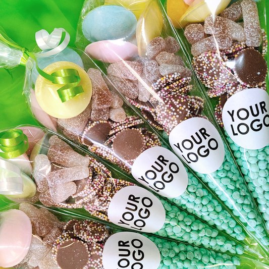 Assorted candies in clear bags with 'Your Logo' labels on a green background