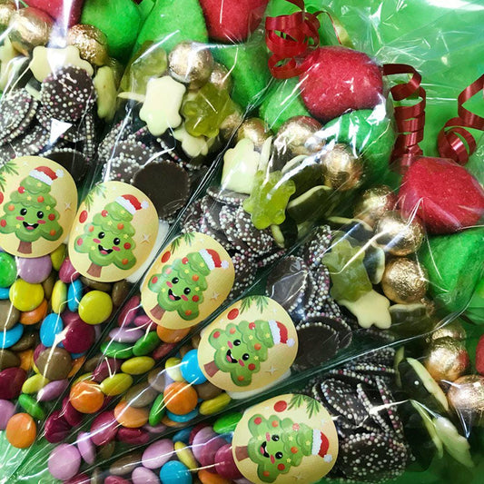 Packaged sweet cones with a Christmas tree design, containing a variety of candies and chocolates, wrapped in transparent plastic.