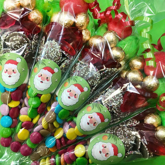 Packaged sweet cones with a cartoon Santa design, containing a variety of candies and chocolates, wrapped in transparent plastic.
