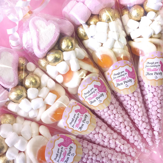 Candy cones with pink and gold decorations and personalized labels on a pink background.