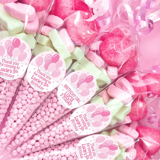 Pink and green candies with personalized labels for a birthday party.