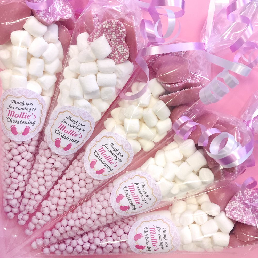 Pink and white candy cones with personalized labels on a pink background