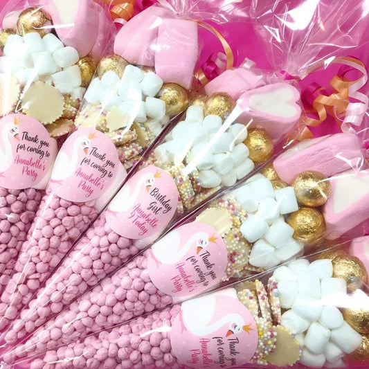 Pre-filled sweet cones for children's parties with a swan sticker design, containing various candies and chocolates.