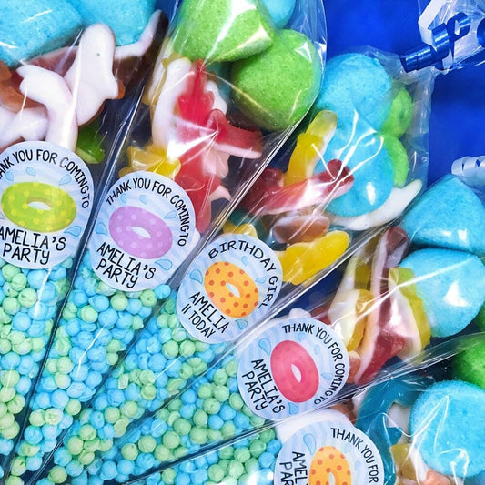 Pre-filled sweet cones for children's swimming parties with colorful candies and personalized labels.