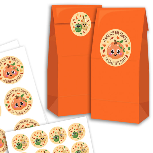 Orange paper party favor bags with a round pumpkin-themed thank you sticker, shown alongside printed sheets of matching round stickers on a white background.