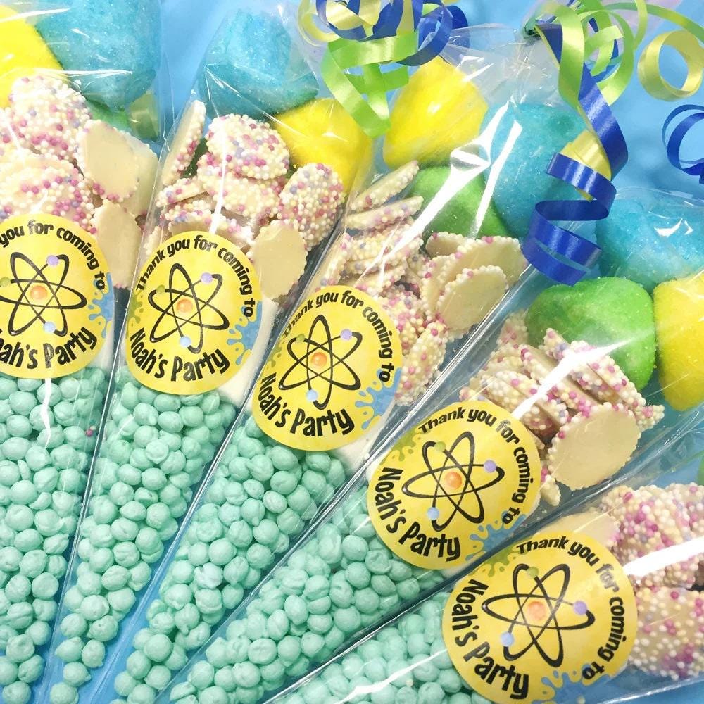 Personalised pre-filled sweet cones for children's birthday parties with science-themed decorations and various candies visible inside the cones.