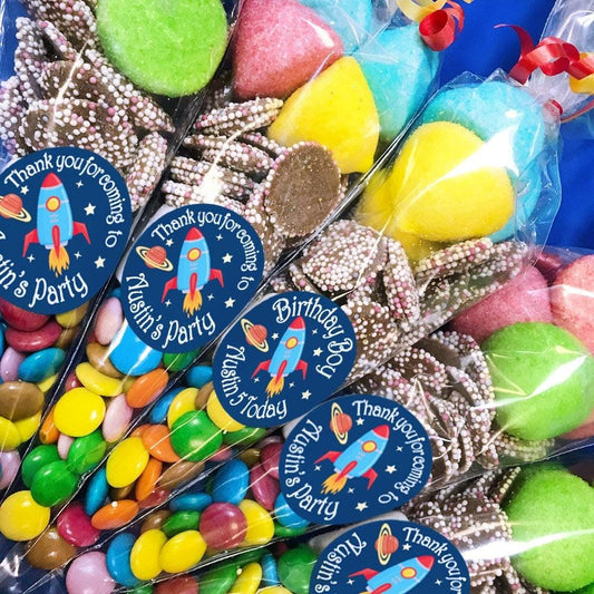 A collection of pre-filled sweet cones with space theme decorations, each cone is adorned with a personalised sticker featuring space-themed graphics.