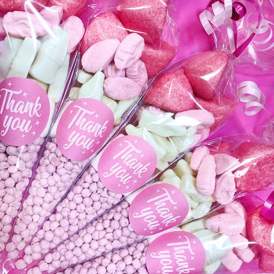 Assorted pink and white candies in clear bags with 'Thank you' labels on a pink background.