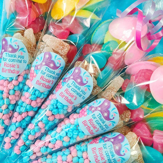 Pre-filled sweet cones with a mermaid theme, containing various colorful candies and personalized with a name label.